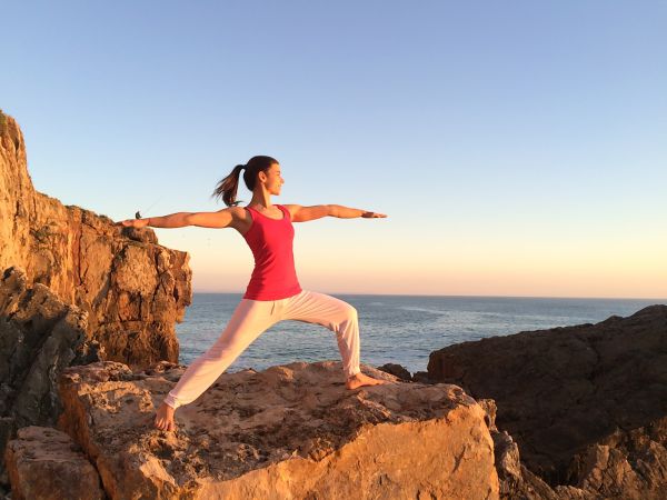 Frau in Yogapose auf Fels am Meer